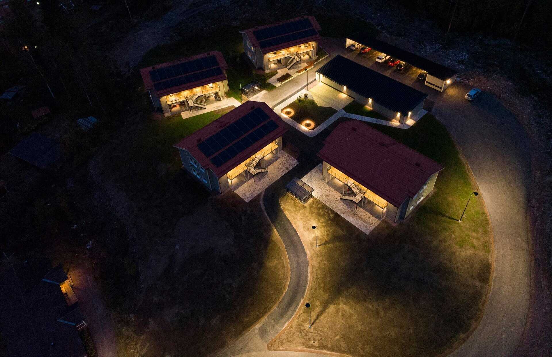 Villa med solpaneler och utomhusbelysning, nattbild av modern bostad.