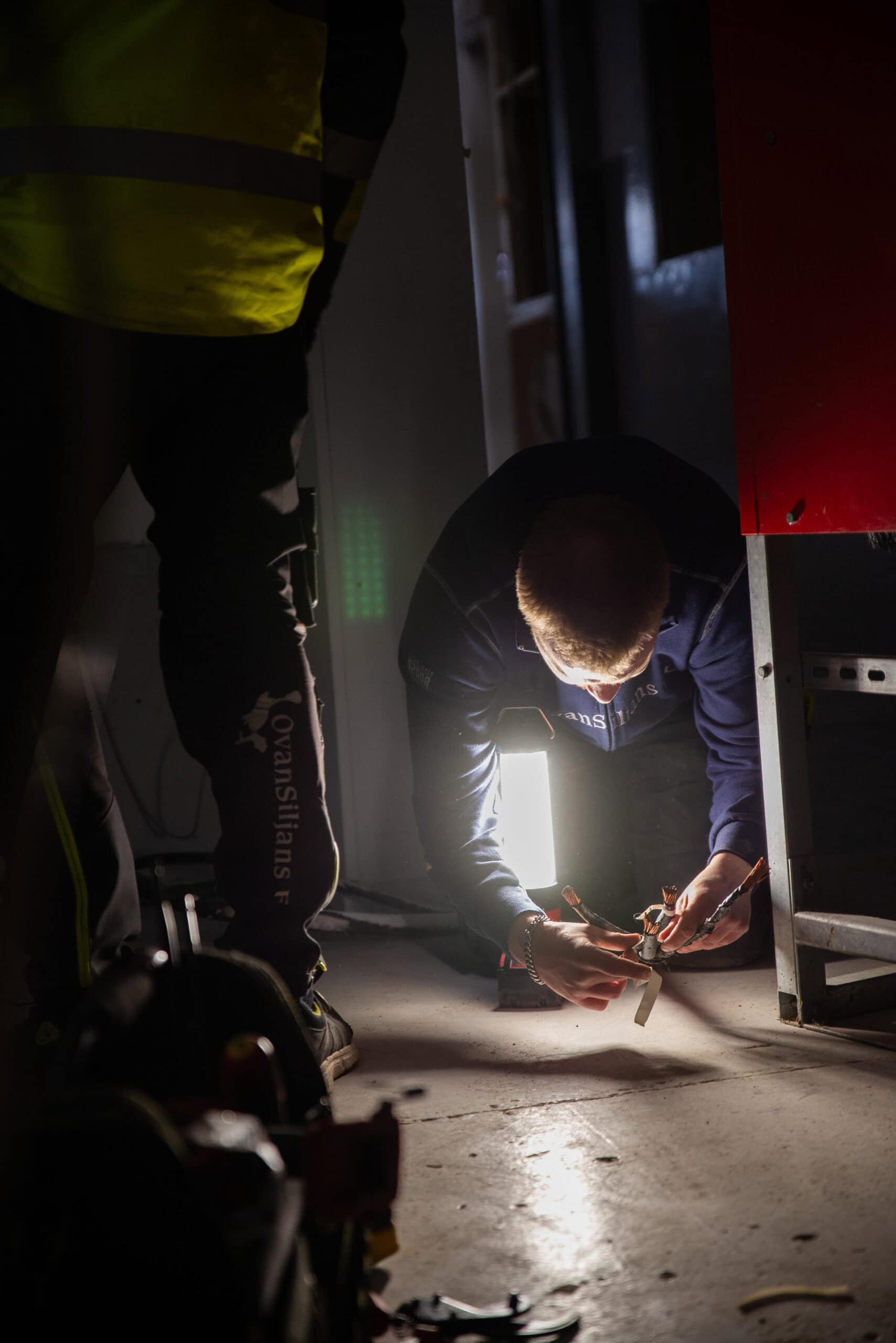 Elinstallatör som arbetar under jord, inspekterar och installerar elutrustning.