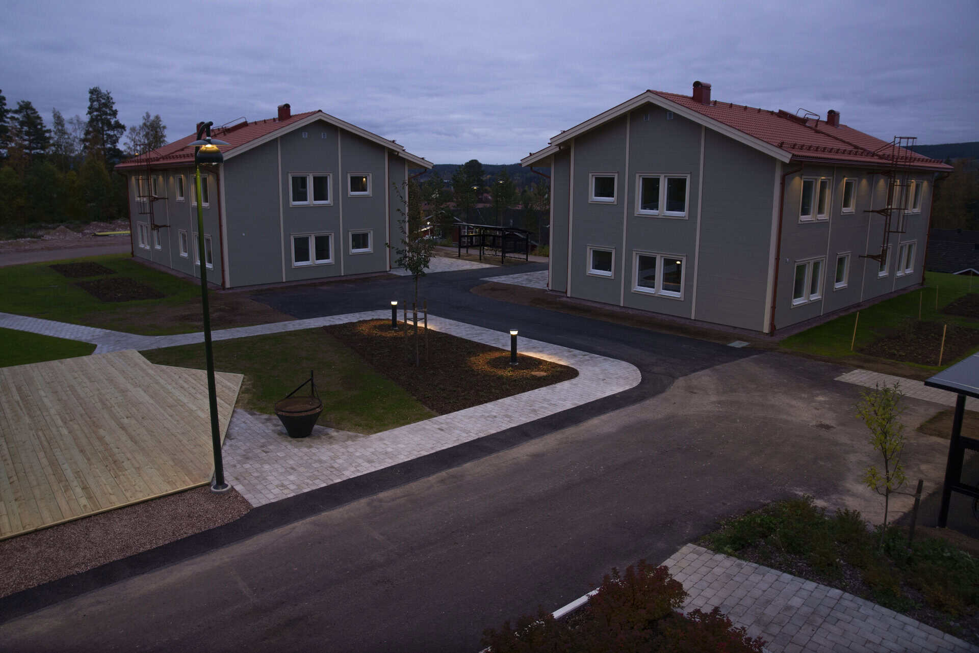 Moderna bostadshus i ett nybyggt område i skymningen.