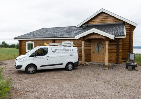 Elföretagets bil framför rustikt hus med elinstallationer i Ovan Siljans El.