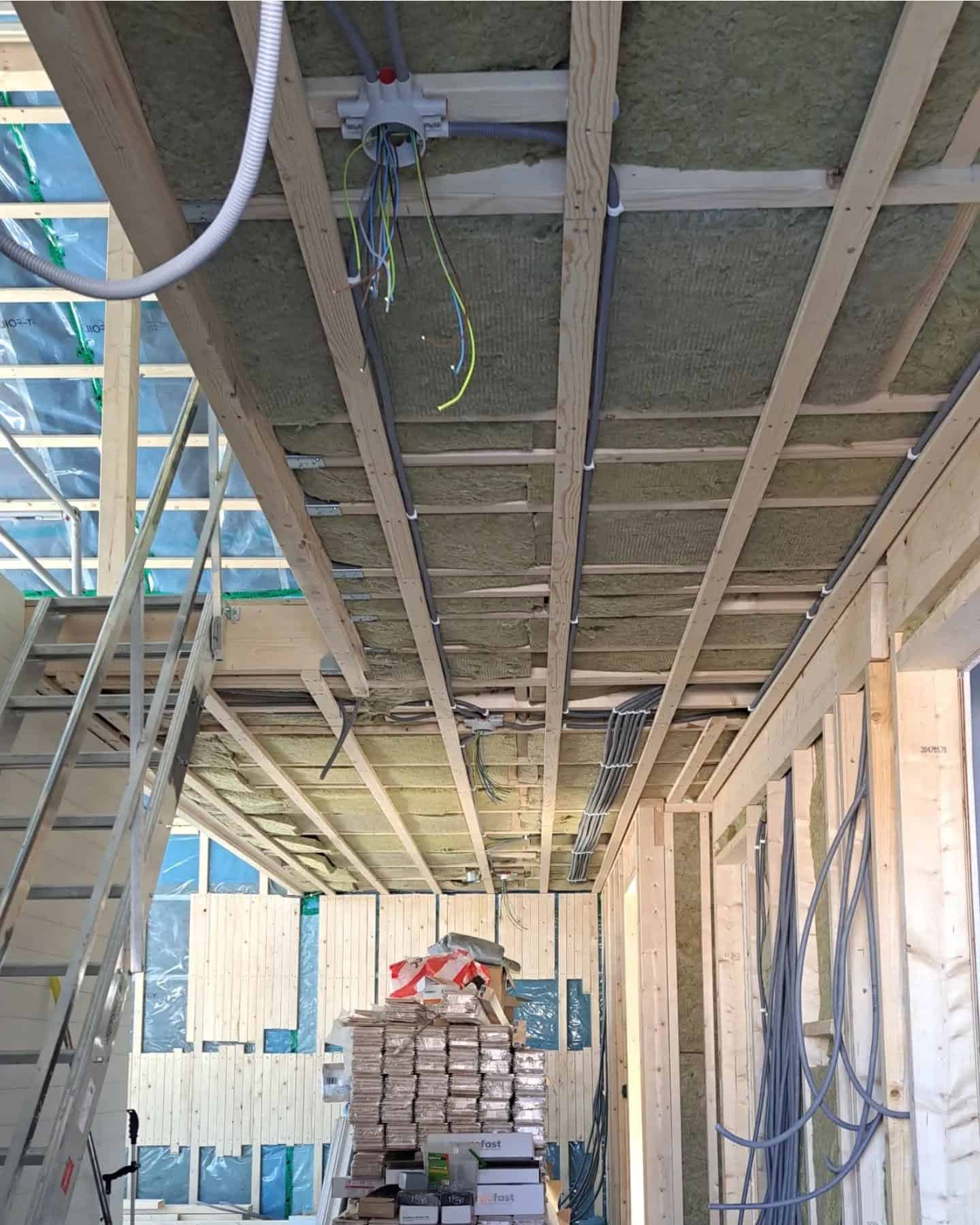 Elinstallation under byggnation med synliga ledningar och takstolar.